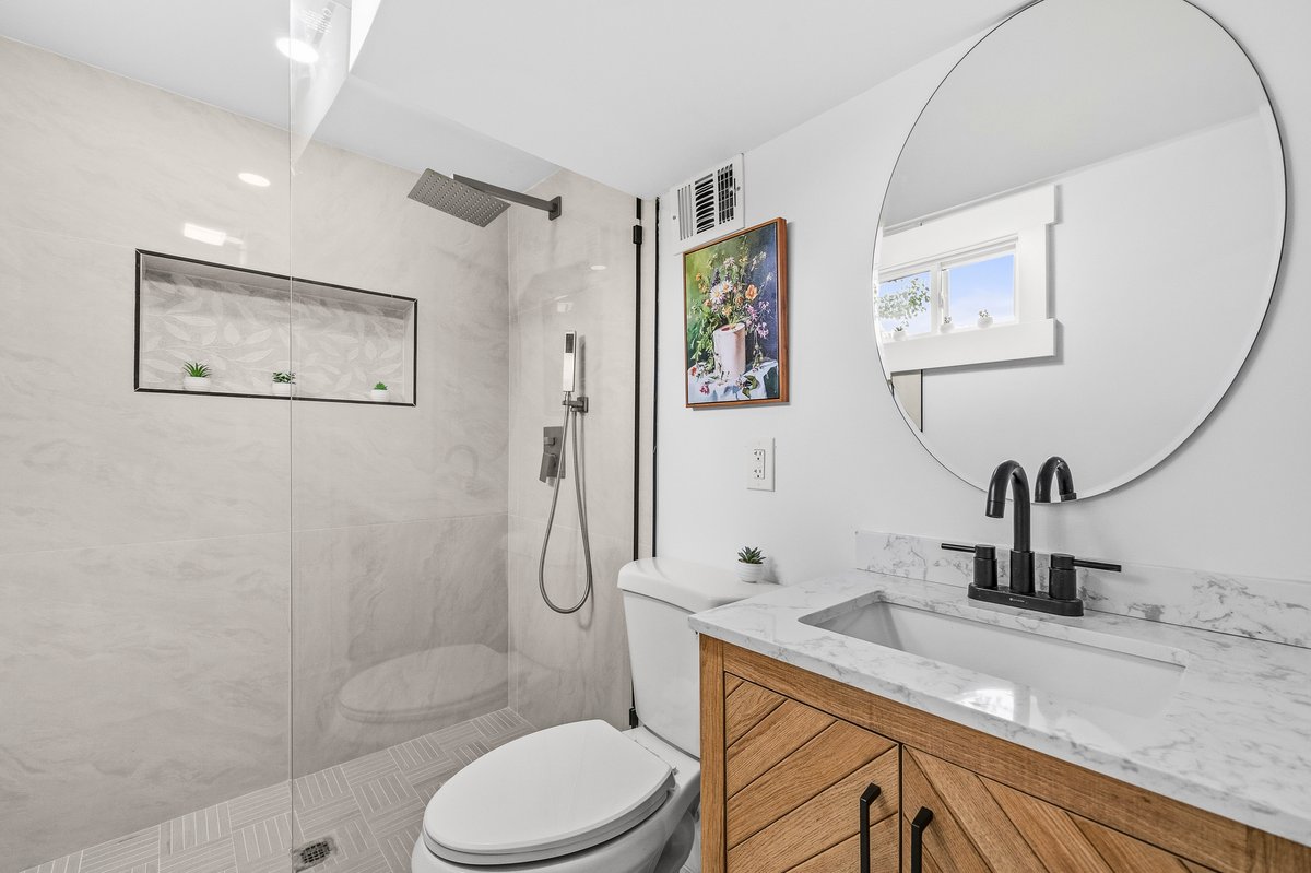 Modern renovated bathroom by KAM Construction with walk-in shower and marble-look tile